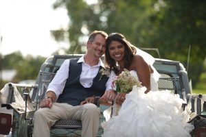 A bride and a groom sitting on the back of a truck