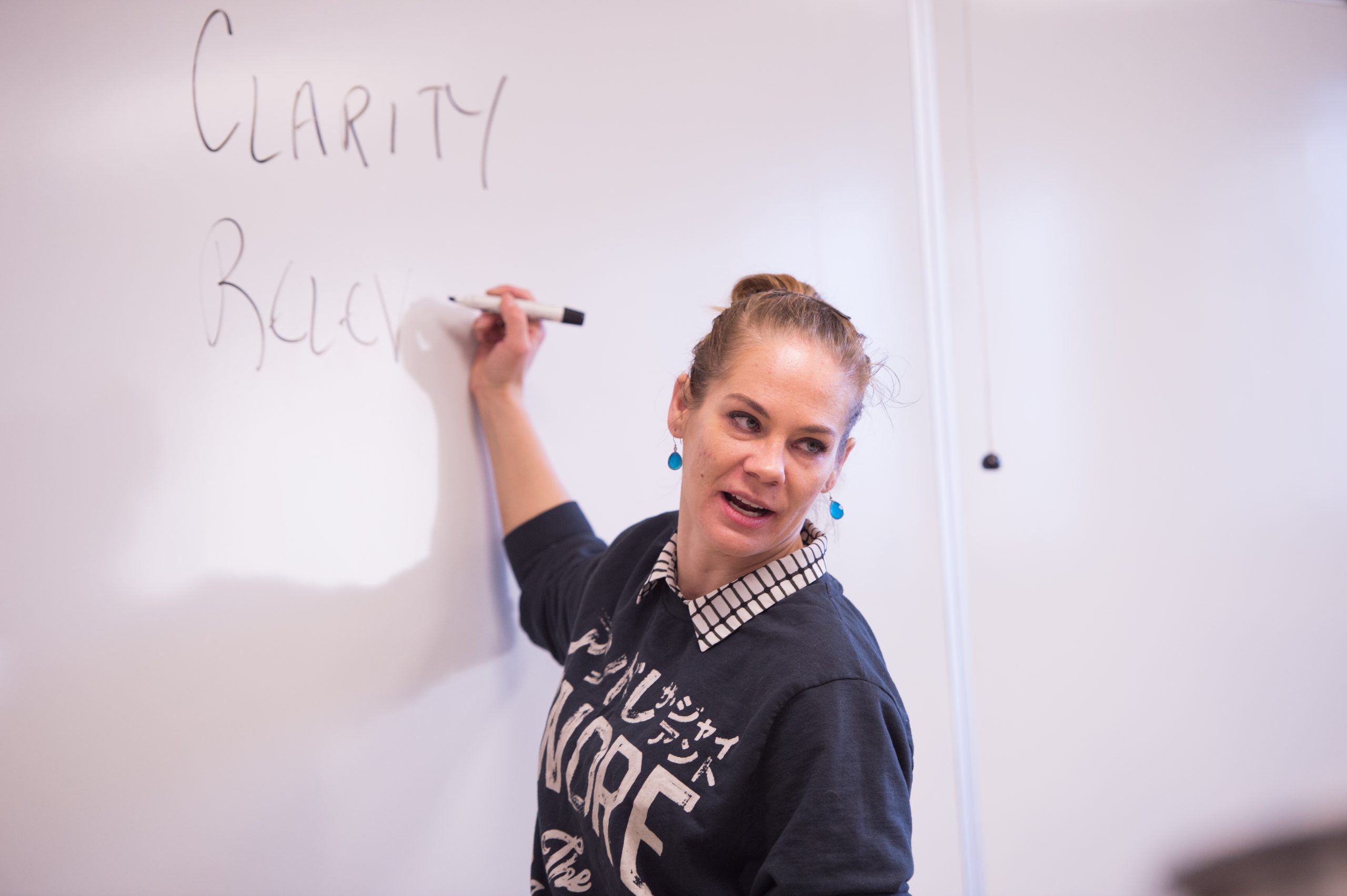 Instructor Julie Kedzie writing on a whiteboard.
