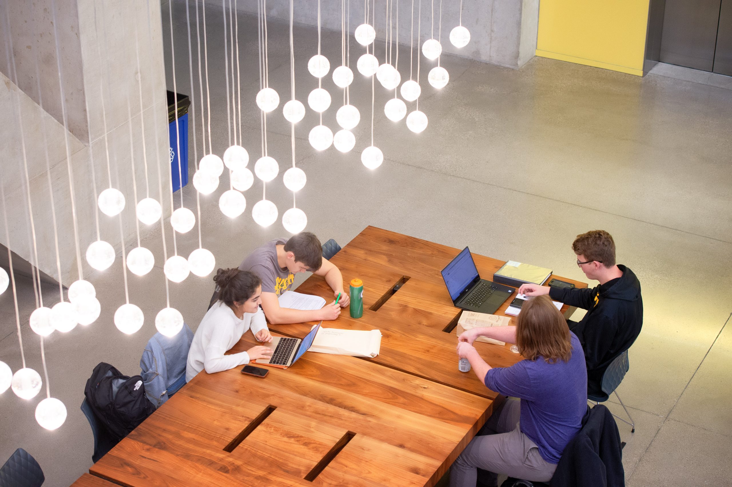 Four students studying at a large table in the Voxman Music Building.