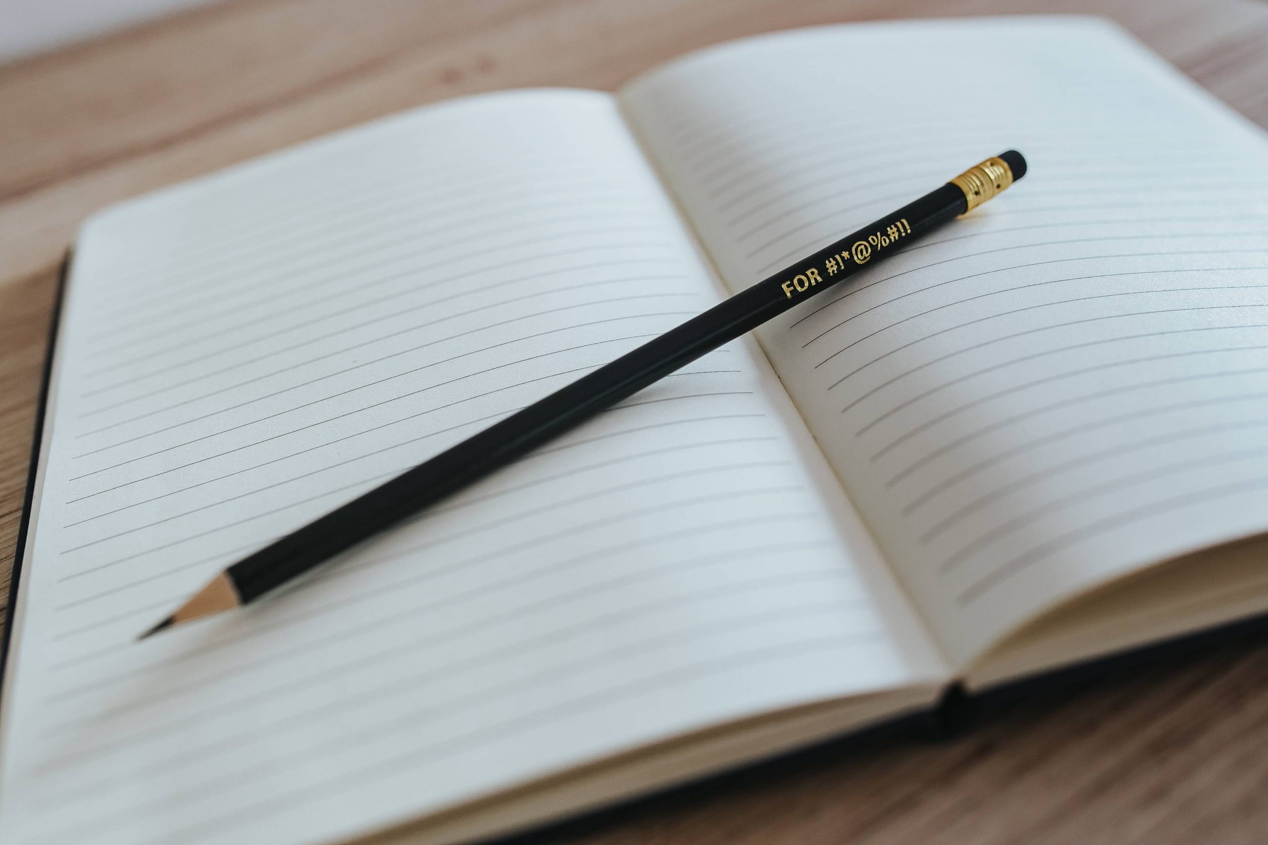 A notebook with a pencil on a wooden desk