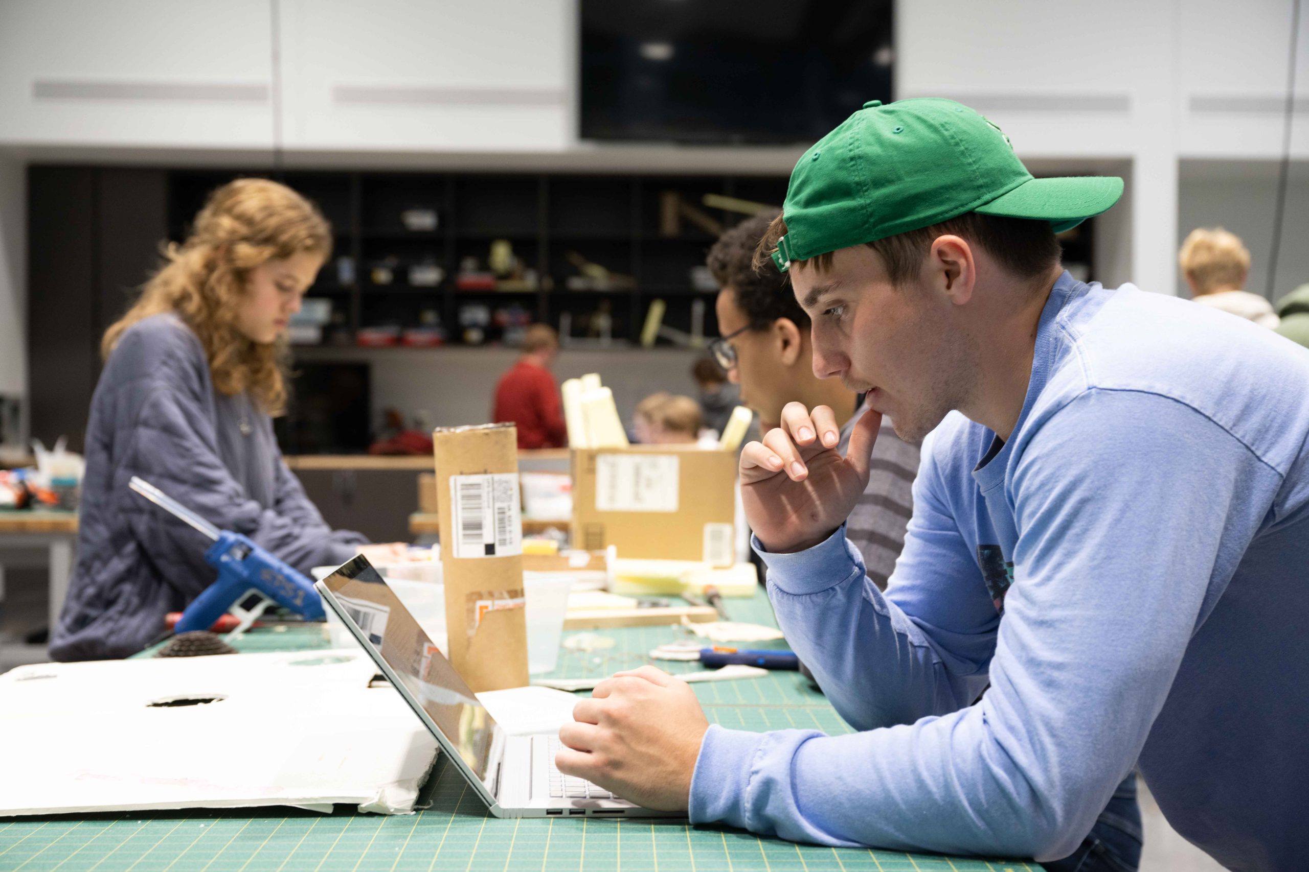 A group of students working in a university lab, working on their computers and making model windmills.