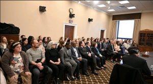 Room of people sitting in chairs looking forward