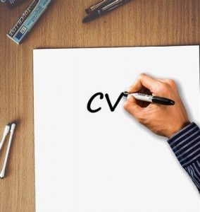 A hand writes the letters CV appear on a piece of paper