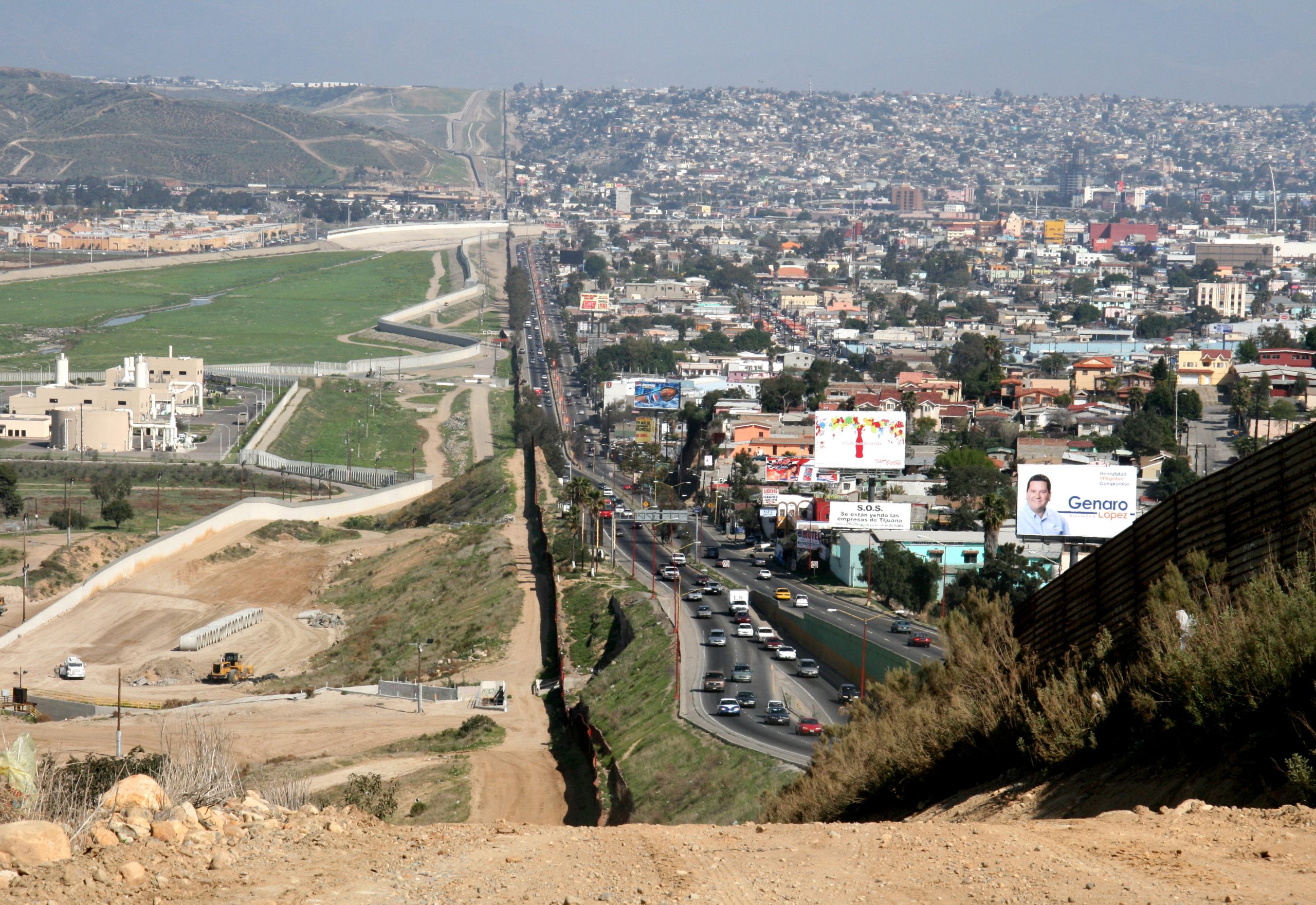 A fence separates a dense populated city and a semi arid ladscape
