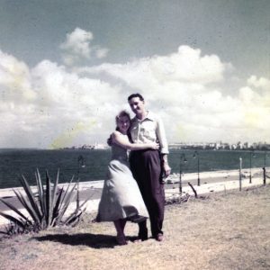 A couple poses for a picture with the malecon in Havana in the background