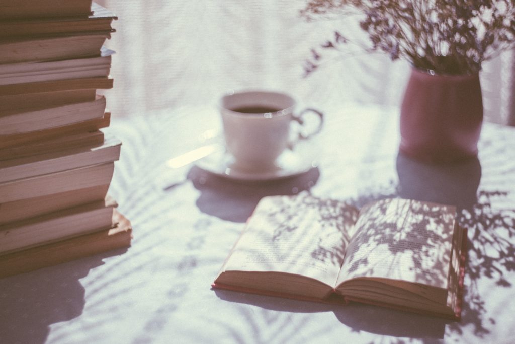 White cup of tea beside an open book