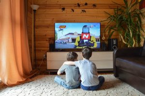 Two kids watch a movie on TV